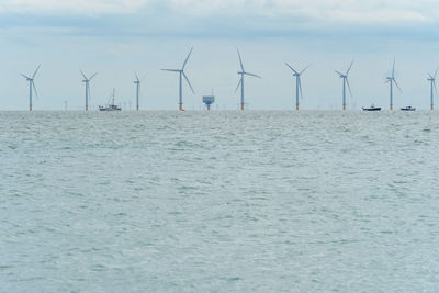 Traditional windmill by sea against sky