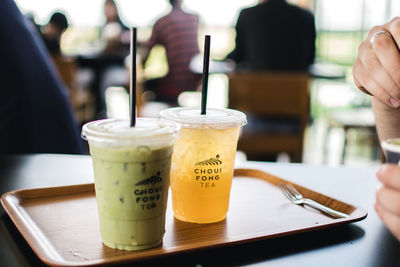 Close-up of hand holding drink served on table at cafe