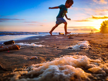 Full length of men on beach against sky during sunset