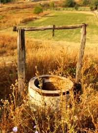 Wooden post on field by fence