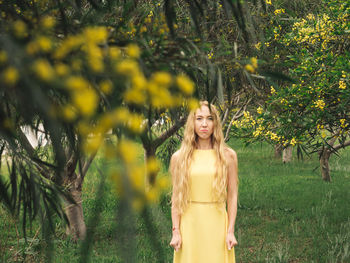 Young woman standing against trees