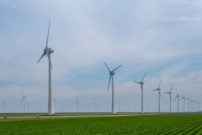 Wind turbines on field against sky