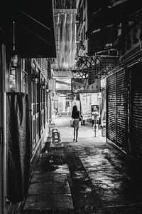 Rear view of people walking on street amidst buildings in city