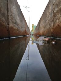 Reflection of buildings in puddle against sky