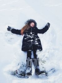 High angle view of girl lying on snow covered land