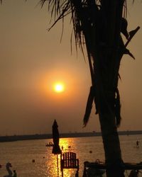 Silhouette tree by sea against sky during sunset
