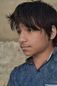 Boy looking away against wall