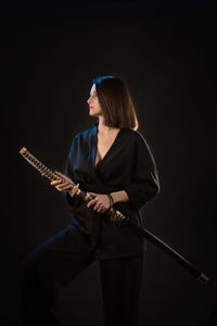 Rear view of woman standing against black background