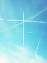 Low angle view of vapor trails against blue sky