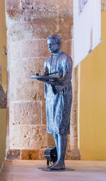 Statue of man standing in front of building