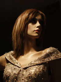 Close-up of young woman against black background