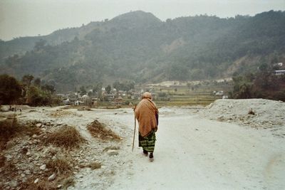 Rear view of man walking on mountain road