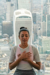 Portrait of young woman standing against cityscape