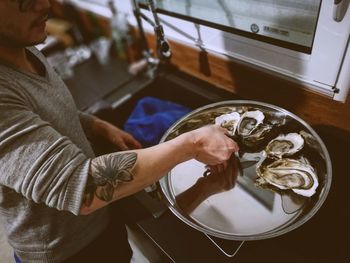 High angle view of man keeping oysters in plate