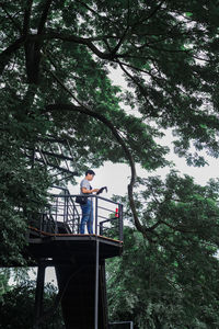 Low angle view of man standing by tree in forest