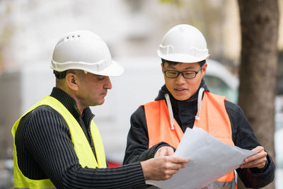 Engineers discussing while standing at construction site