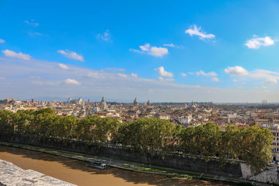 Aerial view of city by river against sky