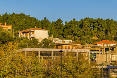 Houses and trees by building against clear sky