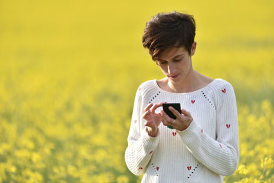 Woman using phone while standing on field