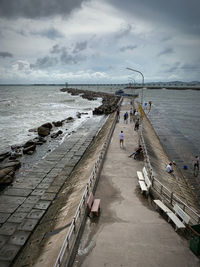 People on pier at beach against sky