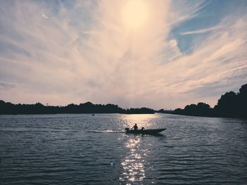 Silhouette man in sea against sky during sunset