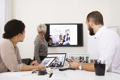 Side view of businesswoman giving presentation to colleagues in office