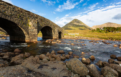 Arch bridge over river against sky