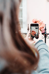 Midsection of woman photographing flower with mobile phone