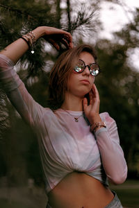 Beautiful young woman wearing eyeglasses against trees