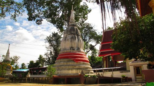 Low angle view of statue against trees and buildings against sky