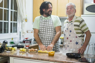 Friends standing by people in kitchen