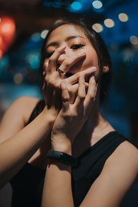 Portrait of woman with hand covering mouth