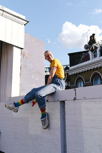 Smiling androgynous person sitting on wall
