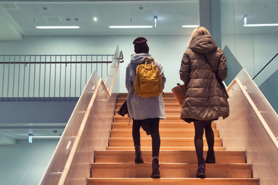Rear view of women walking on staircase