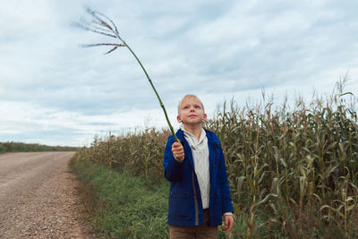 Child in corn field leaves holding twig