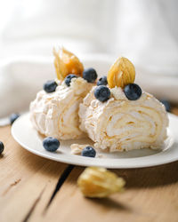 Two pieces of meringue roll with berries on a plate.