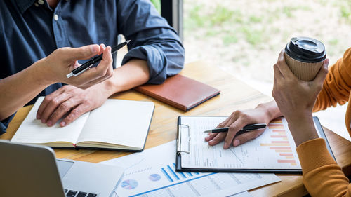 Midsection of business colleagues working on table