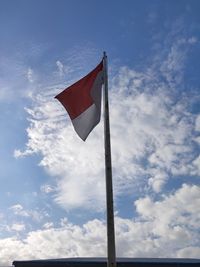 Low angle view of flag against blue sky