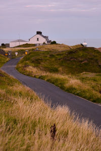 Road amidst field against sky