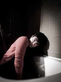Portrait of sad woman sitting in bathtub at home