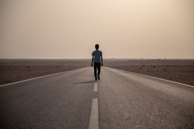 Rear view of man on road against sky