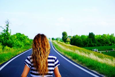 Rear view of woman on road against sky