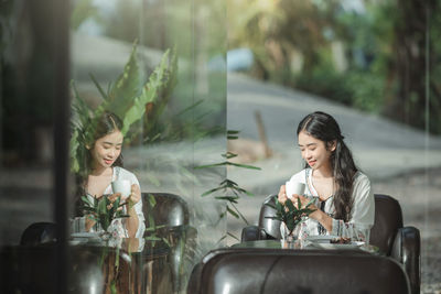 Young woman looking at camera while sitting on table