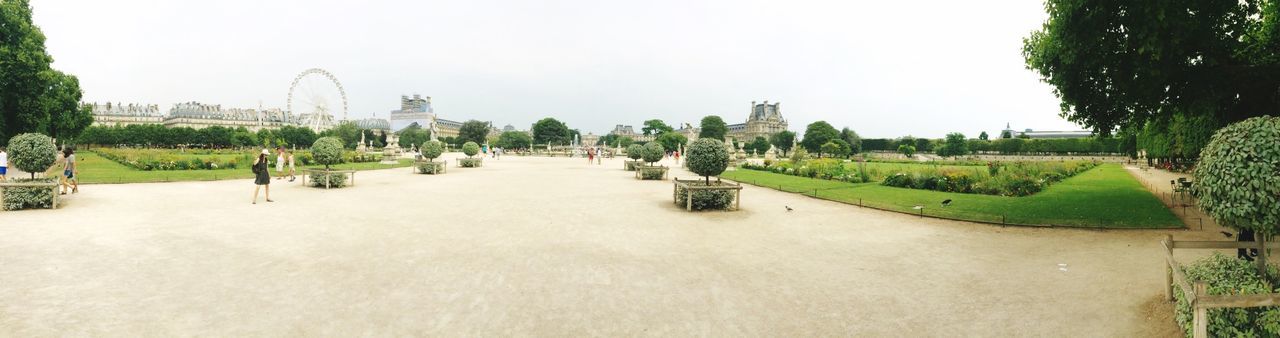 clear sky, built structure, copy space, architecture, tree, building exterior, grass, incidental people, travel destinations, day, tourism, large group of people, in a row, footpath, green color, outdoors, growth, famous place, travel, nature