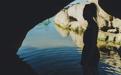 Silhouette man standing on rock by lake