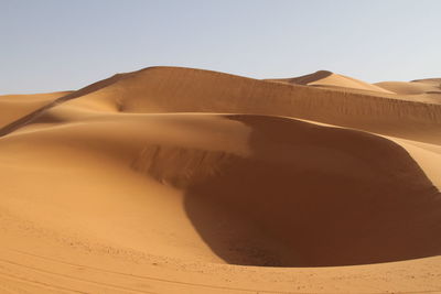 Scenic view of sand dunes at desert against clear sky