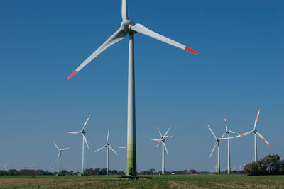 Windmills on field against clear sky