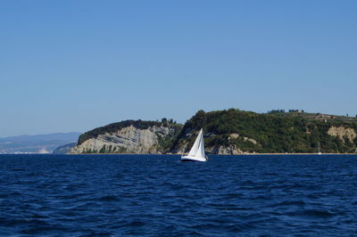 Sailboat in sea against clear blue sky