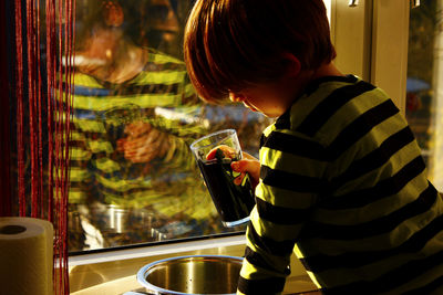 Close-up of boy pouring drink in container