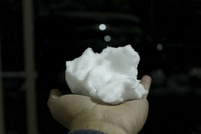 Close-up of hand holding ice cream against black background